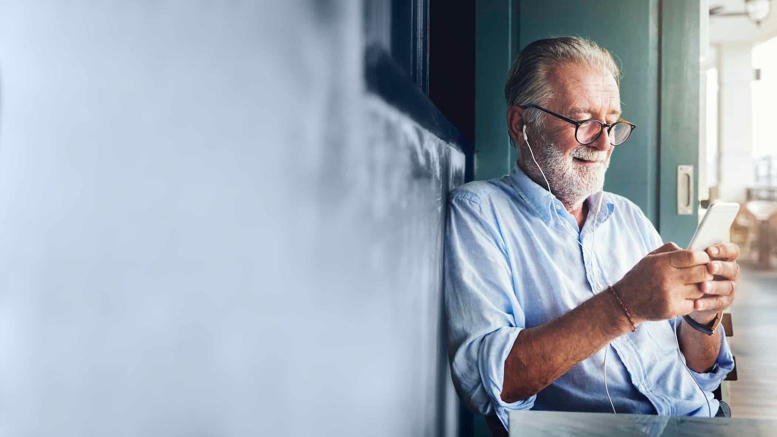Older expat sitting on the floor checking insurance quotes on his phone in Spain