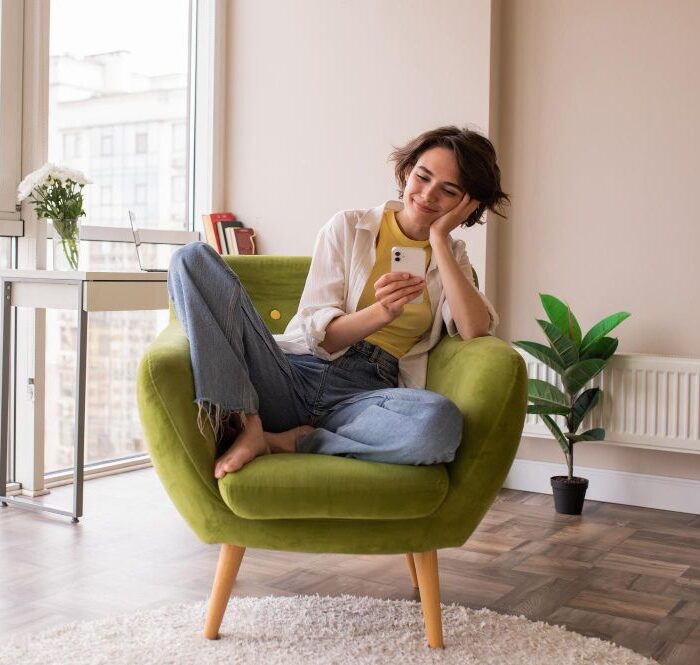 A renters young lady in Spain sitting on a sofa watching the phone
