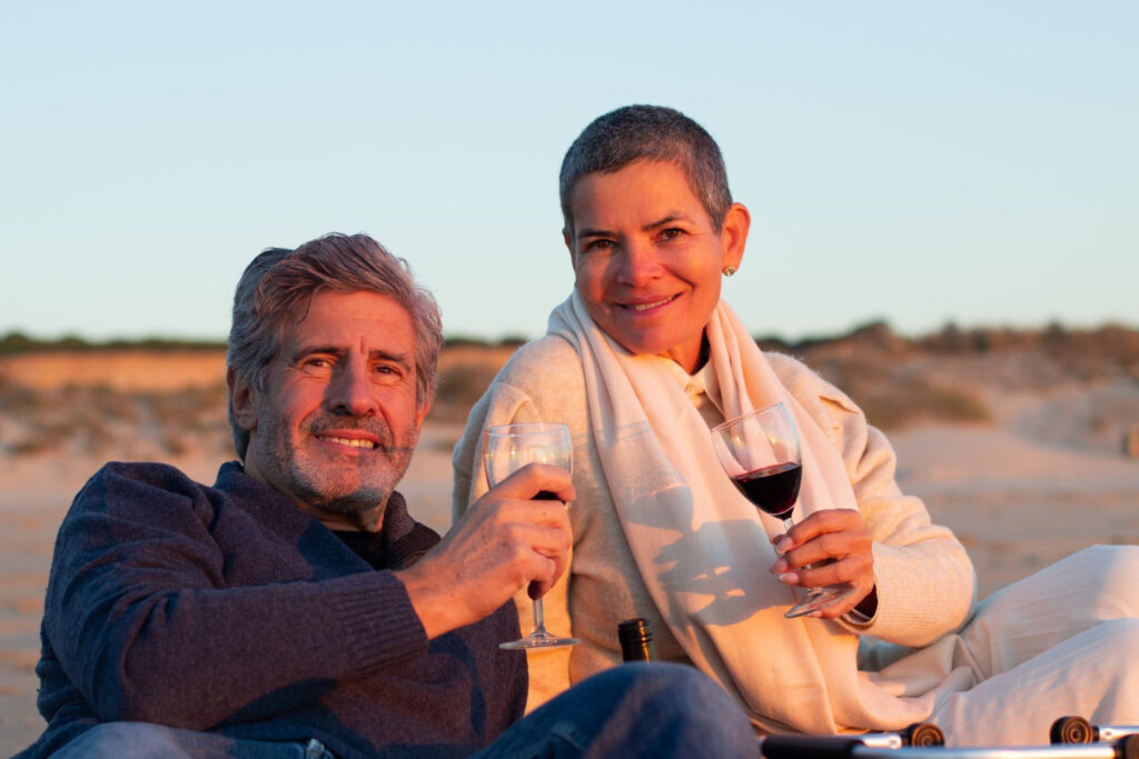 An expat couple in Spain on the beach taking a glass of wine